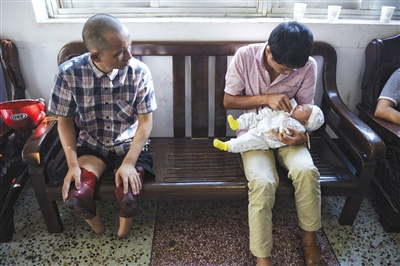 8月29日，彭阳武在派出所等待办理新身份证，他看向旁边一新生儿。
