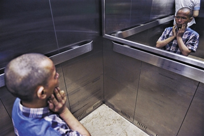 8月29日，浏阳市中医院，彭阳武面对电梯里的镜子观察着自己的脸部出了神。